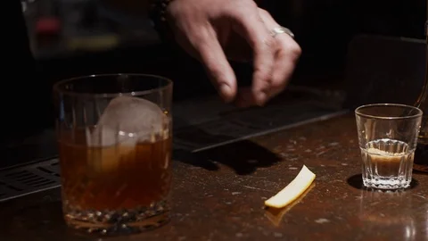 Making a cocktail, squeezing orange peel in glass Stock Footage 124031979