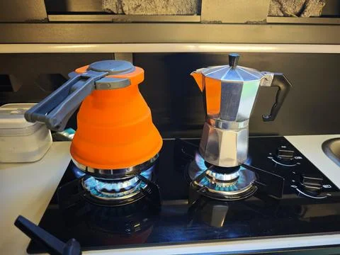 Making coffee and boiling water on a gas stove inside a modern camper van. Stock Photos