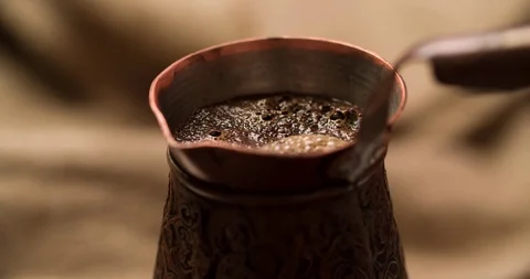 Making Coffee in cezve. Boiling Coffee liquid surface Stock Footage 98266257