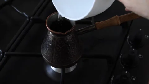 Making coffee in a cezve. Woman's hand lights a gas stove Stock Footage 339616639