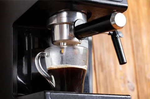 Making coffee in a coffee machine in the kitchen, close-up. Black coffee flowing Stock Photos