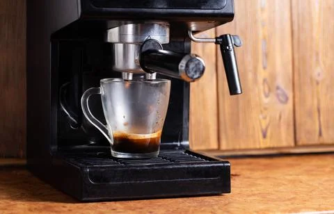 Making coffee in a coffee machine in the kitchen, close-up. Black coffee flowing Photos