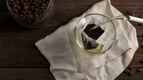 Making coffee with drip coffee bag on a wooden table. Drip brewing coffee. Stock Footage 313847328