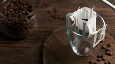 Making coffee with drip coffee bag on a wooden table. Drip brewing coffee Stock Footage 313907718