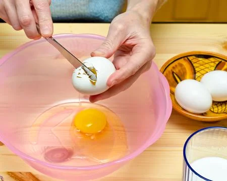 Making cookies. Chacking eggs over wooden background. Stock Photos