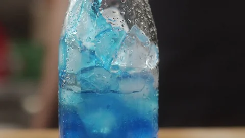 Making cool summer drink with ice is poured blue syrup. Slow motion video Stock Footage 123824481