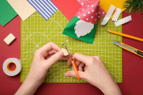 Making a craft. Hands cut out an oval nose from beige paper. Creative process Stock Photos