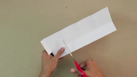 Making crafts. Cut a piece of white card with scissors Vídeos de archivo 168727503