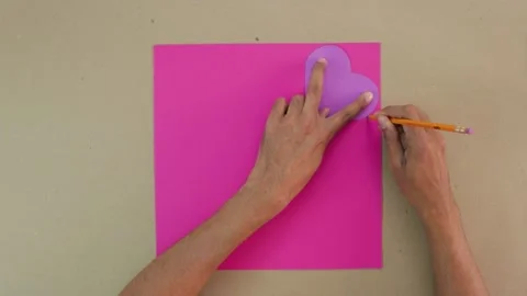 Making crafts. Tracing a heart shape on pink cardboard Stock Footage 168727778