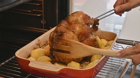 Making a delicious roast chicken. Turning the chicken and potatoes Stock Footage 217984096