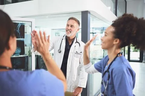 Making a difference together. a team of doctors giving each other a high five in Stock Photos