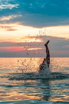 Making a dive into the water under sunset. Stock Photos