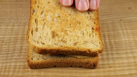 Making a double peanut butter and redcurrant jam sandwich on a wooden board. Stock Footage 319872604