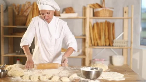 Making dough in bakery - female baker rolling out dough with a rolling pin Stock Footage 341381484