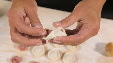Making dumplings. Chef hands forming small handmade ravioli on kitchen table. Video stock 185575343