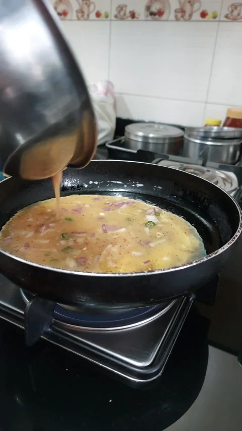 Making egg omlet in pan at home with green chillies,onions,salt and red chi.. Stock Footage 235484629