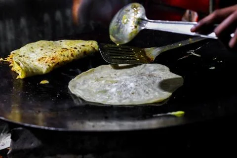 Making of egg roll on a hot frying pan with oil and paratha and salad Foto stock