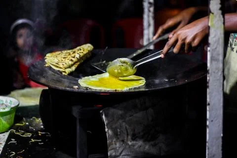 Making of egg roll on a hot frying pan with oil and paratha and salad Stock-Fotos