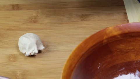 Making flatbread by rolling dough balls into rounds by a rolling pin. Stock Footage 128778689