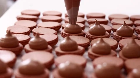 Making french desert macarons. Chef hands with confectionery bag add cream Stock-Footage 237400151