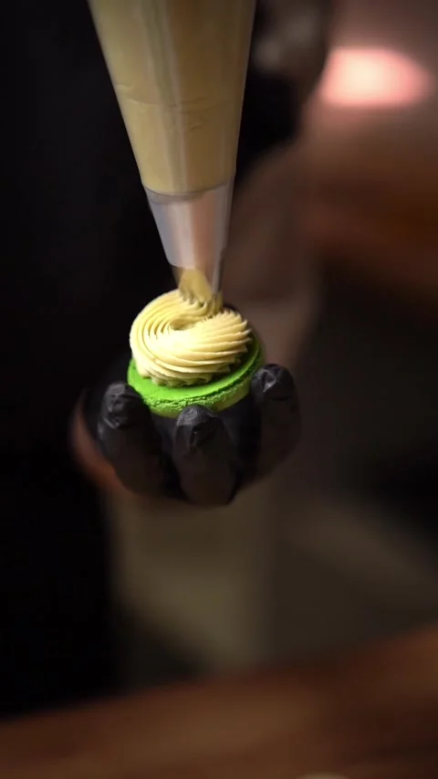 Making french desert macarons. Chef hands with confectionery bag add cream to th Stock Footage 294720475
