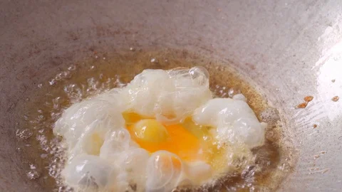 Making fresh fried egg in hot oil 動画素材 129818957