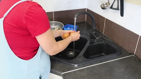 Making fried eggs with vegetables at home. A woman washes vegetables under the t Stock Footage 317542823