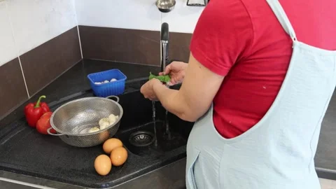 Making fried eggs with vegetables at home. A woman washes vegetables under the t Stock Footage 317542994