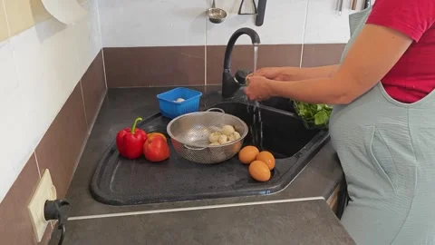 Making fried eggs with vegetables at home. A woman washes vegetables under the t Stock Footage 317544277