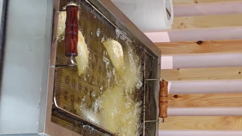 Making fried food in a kitchen with bubbling oil in a fryer Stock Footage 340462885