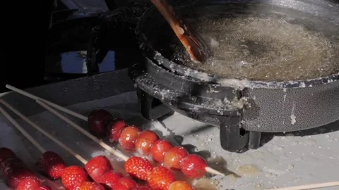 Making fruits in boiling caramel close-up. Chinese winter sweet dessert Tanghulu Stock Footage 265913902