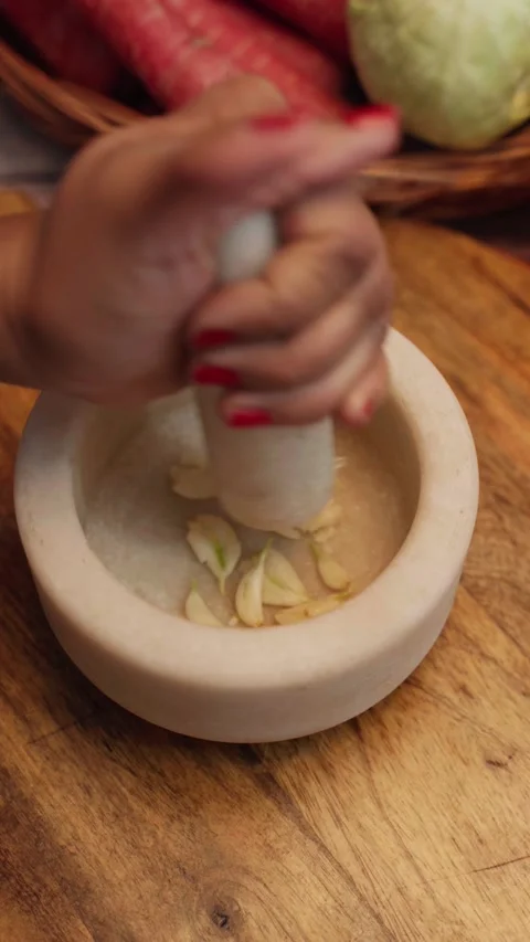 Making garlic paste in a white stone mortar on wooden chopping board. Stock Footage 283361453