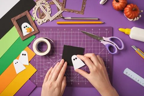 Making a ghost portrait craft. Hands glue the silhouette of a ghost onto th.. Stock Photos