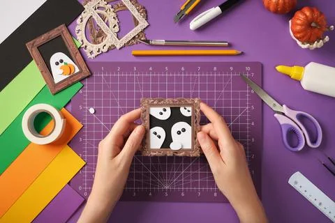 Making a ghost portrait craft. Hands holding the finished craft against a b.. Stock Photos