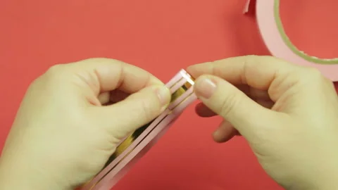 Making a gift bow of pink ribbon on a red background. Time laps 库存影片 100194722