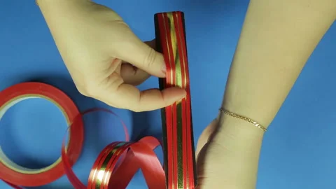 Making a gift bow in red on a blue background. Time laps 库存影片 98505744