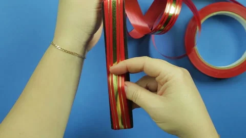 Making a gift bow of red ribbon on a blue background. Time laps Stock Footage 98826148