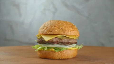 Making a Hamburger with Barbecued Beef Patty, onion, melted cheese, A hamburger Stock Footage 336579398