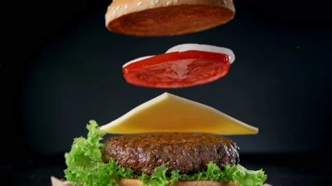 Making a Hamburger with Falling Beef Patty, Cheese, Sesame Bun and Veggetables Stock Footage