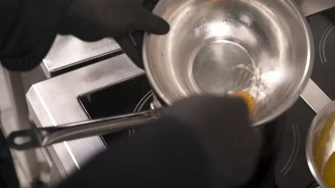 Making hollandaise sauce by adding melted butter to egg and whisking. Haute Stock Footage 105493407