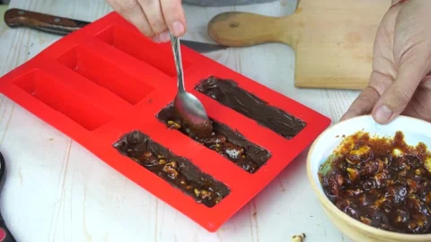 Making homemade chocolate bars with nuts and caramel in silicone mold Video stock 150673451
