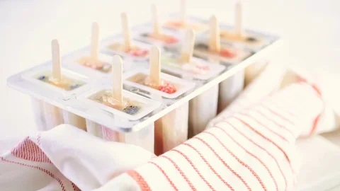 Making homemade fresh fruit popsicles with apple juice in frozn ice pop maker Stock Footage