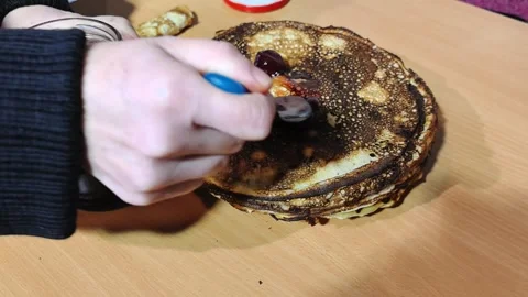 Making homemade pancakes with cherry jam in a cozy kitchen setting Video stock 328439431