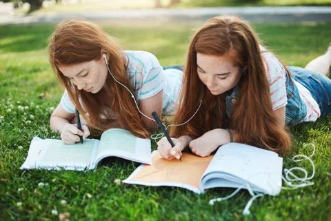 Making homework can be fun. Outdoor shot of two attractive redhead girls with Stock Photos