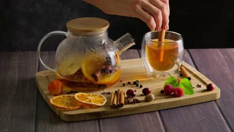 Making hot fruit tea with orange and raspberry at home, woman's hand putting a Stock Footage 223129505