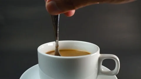 Making hot instant coffee in a white cup. Hand stirring hot coffee Stock Footage 129815666