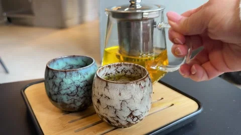 Making hot tea on the kitchen table. Boiling water is poured from the kettle Stock Footage 323924263