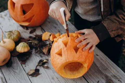 Making a jack o lantern. Hands carving halloween pumpkin on rustic wooden t.. Stock Photos