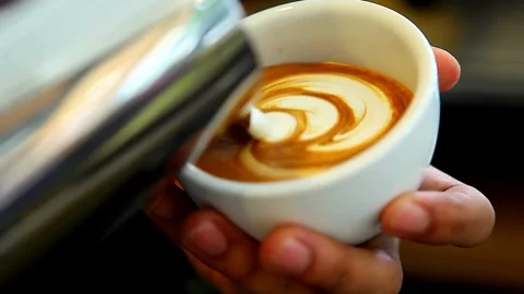 Making of latte art. Latte is a coffee drink made with espresso and steamed 動画素材 334650064