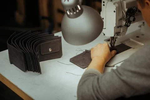 Making leather wallets on a sewing machine by a craftsman on a white table Stock Photos